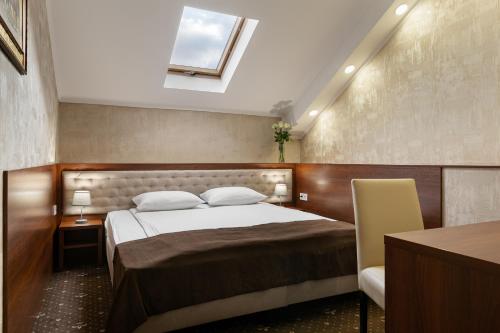 a bedroom with a bed and a desk and a window at Optima Collection Gallery Poltava in Poltava