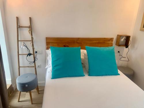 a bedroom with a bed with blue pillows and a ladder at Casa Via De La Plata in Cáceres