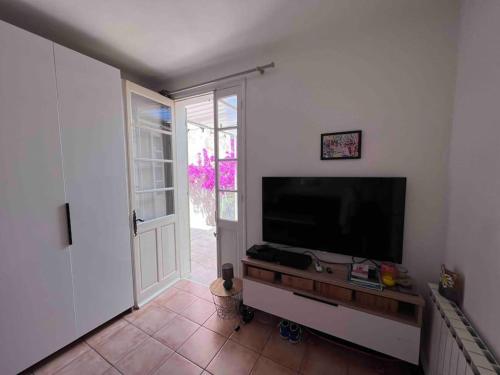 een woonkamer met een flatscreen-tv en een deur bij Maison dans les rues piétonnes du vieux Hyères in Hyères