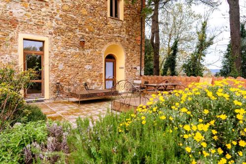 a stone house with a garden with yellow flowers at Agriturismo Bio Fattoria di Pietra in Giuncarico