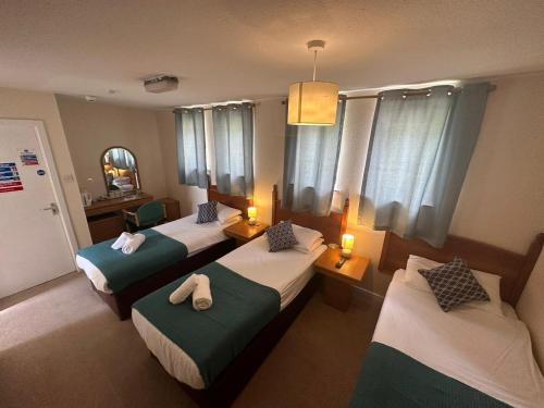 a hotel room with three beds and two lamps at Mackay's Spa Lodge Hotel in Strathpeffer