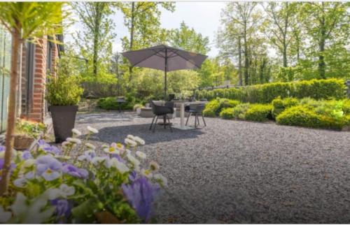 un patio con sombrilla, sillas y flores en Levasion nature, en Beauraing