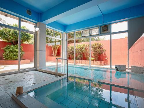 a large swimming pool with a blue ceiling and windows at Hotel Murasakimura in Yomitan