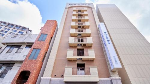 Toyoko Inn Okinawa Naha Kokusai-dori Miebashi-eki في ناها: مبنى طويل وبه شرفات على جانبه