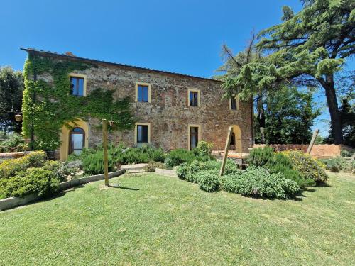 een groot bakstenen huis met een tuin ervoor bij Agriturismo Bio Fattoria di Pietra in Giuncarico