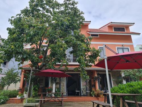 a house with tables and umbrellas in front of it at La Em Boutique Villa in Da Lat