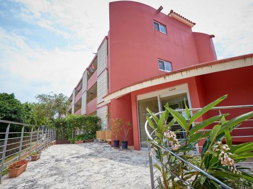 a red building with plants in front of it at Hotel Murasakimura in Yomitan