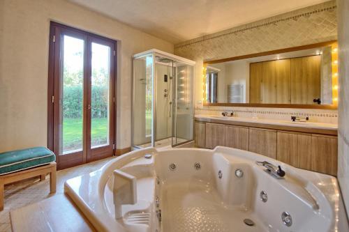 uma grande casa de banho com uma banheira e um espelho grande em Villa Dolce Vita by PosarelliVillas em Punta Ala