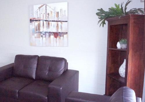 a living room with a brown couch and a painting at Maude St Apartments in Shepparton