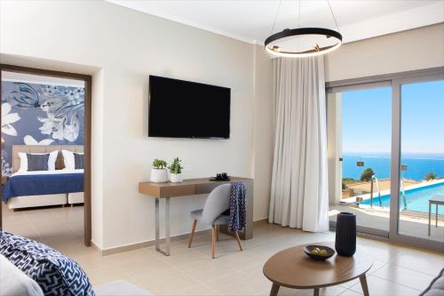 a hotel room with a bed and a desk and a tv at Ajul Luxury Hotel & Spa Resort, a Registry Collection Hotel in Agia Paraskevi