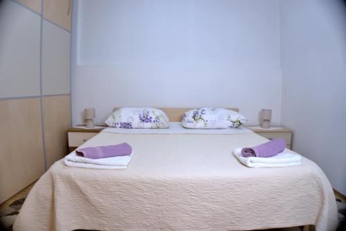 - une chambre avec un lit et des serviettes pourpres dans l'établissement Apartments Meli, à Zadar