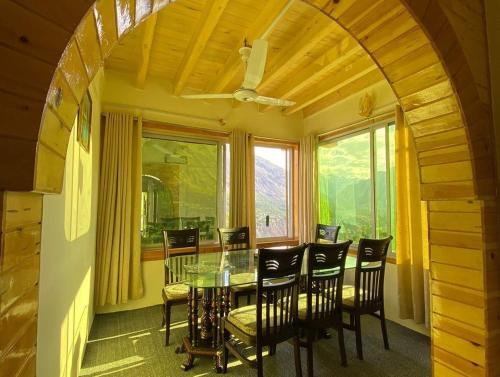 ein Esszimmer mit einem Tisch, Stühlen und einem Fenster in der Unterkunft Hunza Lounge in Hunza
