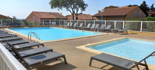 basen z leżakami obok niego w obiekcie Holidayland Résidence Beau Soleil villa 5 couchages avec piscine w mieście Narbonne-Plage