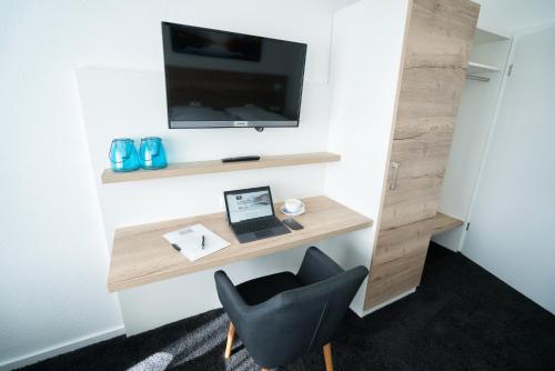 a room with a desk with a laptop and a chair at Hotel zur Sonne GmbH in Bodelshausen