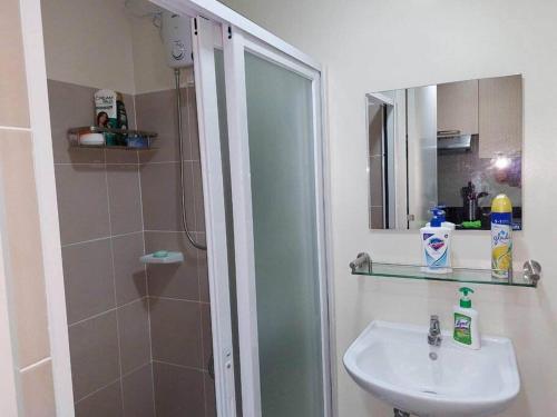 a bathroom with a sink and a shower with a mirror at ZackG Serene Homestay at Brenthill 210 Baguio in Baguio