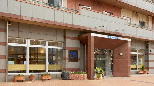 a building with potted plants in front of it at Toyoko Inn Tokyo Shinagawa-eki Takanawa-guchi in Tokyo