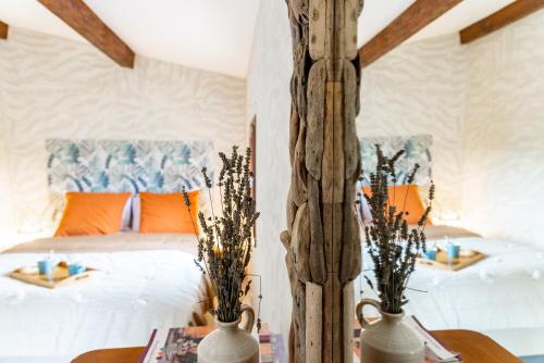 1 Schlafzimmer mit einem Bett mit orangefarbenen Kissen und 2 Tischen in der Unterkunft Au petit bonheur in Bédoin