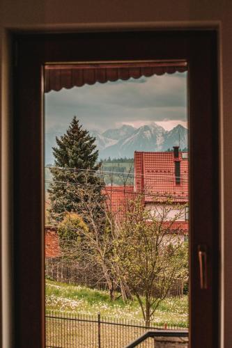 a window with a view of a building and a tree at Poddasze dla Znajomych - apartament z gorącą balią nad Jeziorem Czorsztyńskim - okolica Czorsztyn, Szczawnica, Velo Czorsztyn, Krościenko, Zakopane, Gorce, Pieniny, Tatry in Kluszkowce