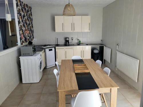 a kitchen with a wooden table and white cabinets at Un petit coin de paradis in Gavarret