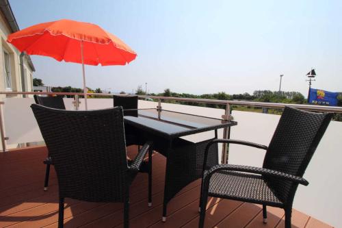 einen Tisch und Stühle mit Sonnenschirm auf dem Balkon in der Unterkunft Ferienwohnung Emely in Sassnitz
