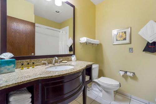 a bathroom with a sink and a toilet and a mirror at Best Western Plus Plaza by the Green in Kent