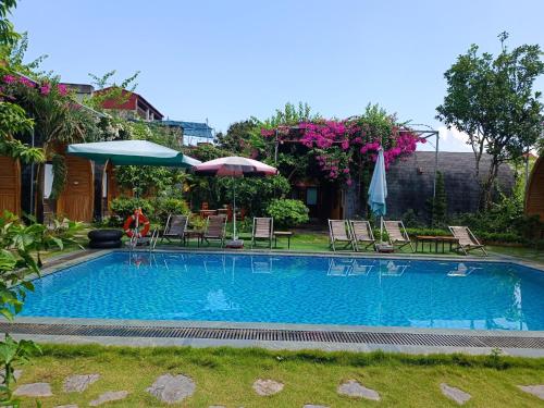 寧平的住宿－Tam Coc Village Bungalow，庭院内带椅子和遮阳伞的游泳池