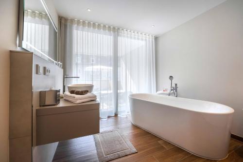 La salle de bains est pourvue d'une baignoire blanche et d'une grande fenêtre. dans l'établissement Lichtenberg Lodges, à Lichtenberg