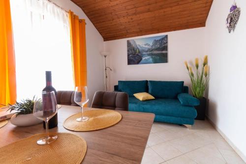 a living room with a blue couch and two wine glasses at Apartment Aria 150 meters from the beach - by TA Leut agency in Privlaka