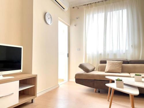 a living room with a couch and a tv at Peaceful Condo in City Center in Durrës