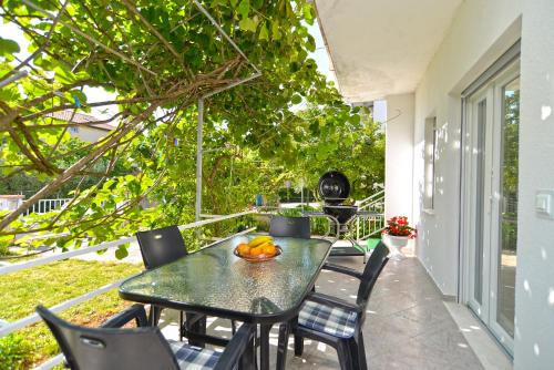 a table and chairs on a porch with a bowl of fruit on it at Apartments Mala Vala 925 - adapted in Fažana