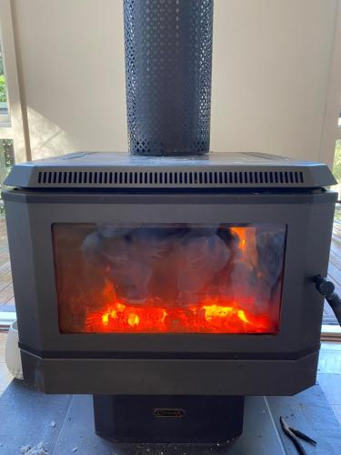 a stove with a fire inside of it at Sassafras Treehouse Private home in the Dandenong Ranges, Victoria in Sassafras