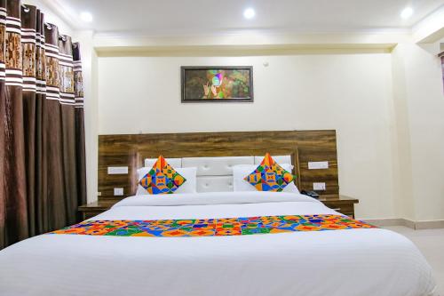 a bedroom with a large white bed with colorful pillows at FabHotel The Eden in Dharamshala