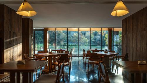 un restaurante con mesas, sillas y ventanas grandes en Wish Garden Huangshan, en Yi