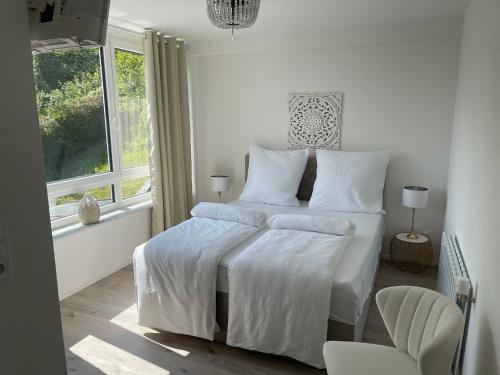 a white bedroom with a white bed and a window at Gästehaus Paulina in Cochem