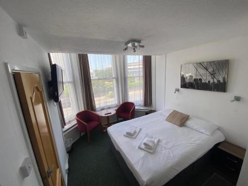 a hotel room with a bed with two towels on it at OYO Carlton Court Hotel in Eastbourne