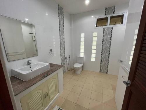 a white bathroom with a sink and a toilet at Daras house in Ban Klam