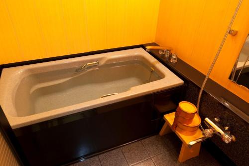 a bath tub in a bathroom with yellow walls at Kinzan in Kobe