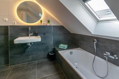 Un baño con lavabo, bañera y espejo. en Landhaus Seewind mit Sauna, en Dornum