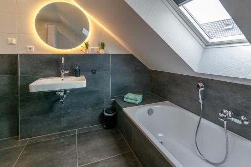 a bathroom with a sink and a tub and a mirror at Landhaus Seewind mit Sauna in Dornum