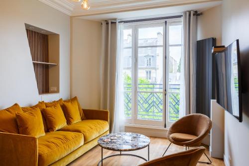 - un salon avec un canapé jaune et une fenêtre dans l'établissement The Eiffel Tower Cosy Nest, à Paris