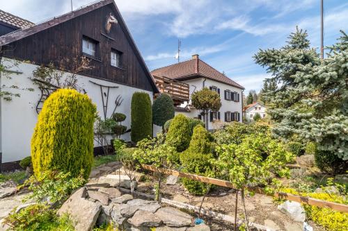 a garden in front of a house with bushes at Pension a restaurace Regina in Větřní