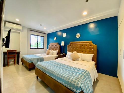 a bedroom with two beds and a blue wall at Paradores de Vigan in Vigan