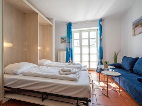 une chambre avec deux lits et un canapé bleu dans l'établissement Feriendorf Rugana - Klassik 1-Raum Appartement mit Terrasse B32, à Dranske