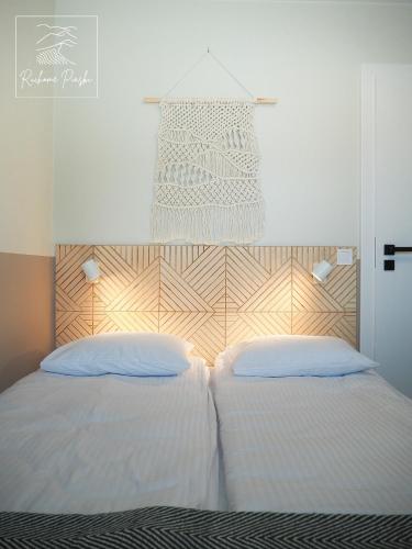 two beds with white sheets and a wooden headboard at Ruchome Piaski in Łeba