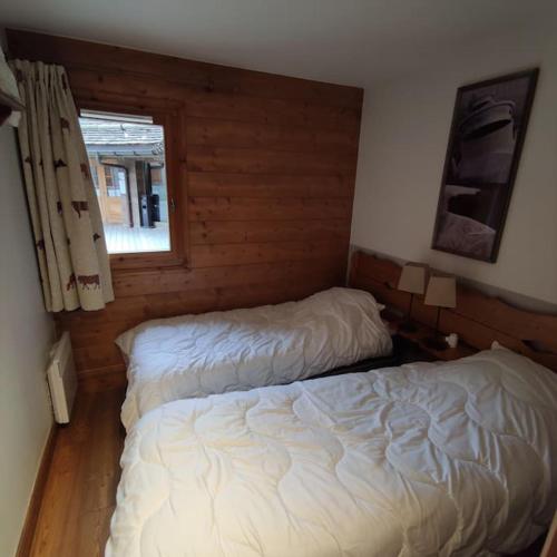 une chambre avec deux lits et une fenêtre dans l'établissement Appartement 4 pers avec piscine commune Carroz d'Araches, aux Carroz d'Arâches