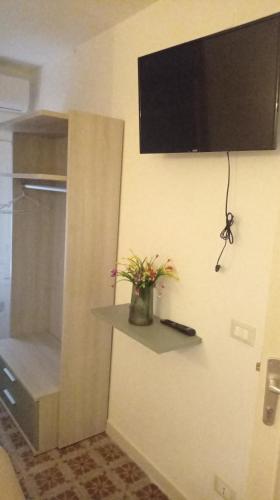 a room with a television and a vase with flowers on a wall at casa ANNA in Trapani
