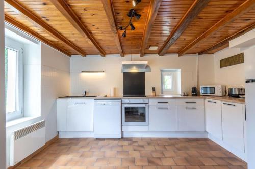 a kitchen with white appliances and a wooden ceiling at Le Cocon de la Vallée in Saint-Julien-de-Chédon