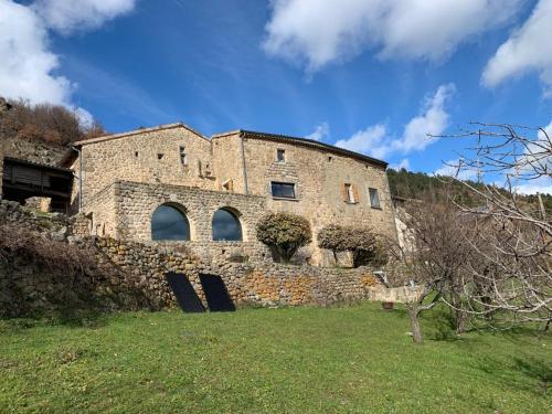 un ancien bâtiment en briques sur une colline avec un champ vert dans l'établissement Les chambres de la Bastide, à Saint-Sauveur-de-Montagut