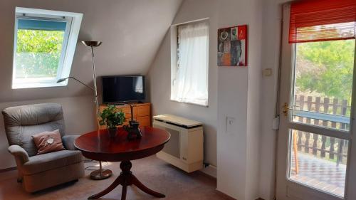 sala de estar con mesa, silla y TV en Szalakóta Ház, en Balatongyörök