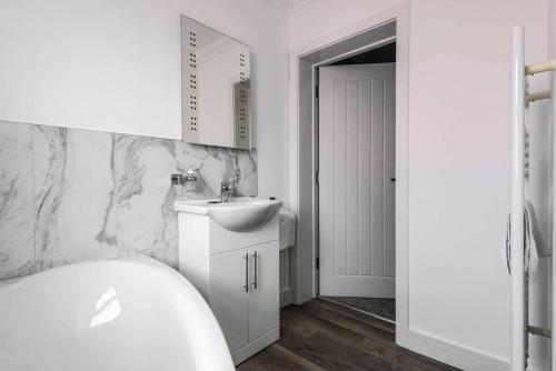 a white bathroom with a sink and a mirror at Gillian House - Charming Broadstairs apartment in Kent